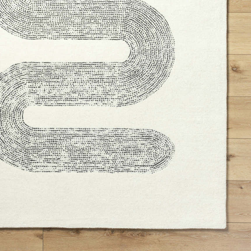 Close-up of the Saura Wool Area Rug. Ivory rug with a contemporary charcoal dotted line pattern on a wood floor. Corner