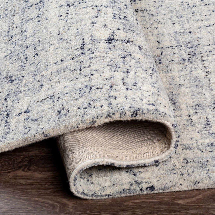 Close-up of the Tanana Area Rug, a hand-tufted wool rug with a black, cream, and gray speckled contemporary design. Fold