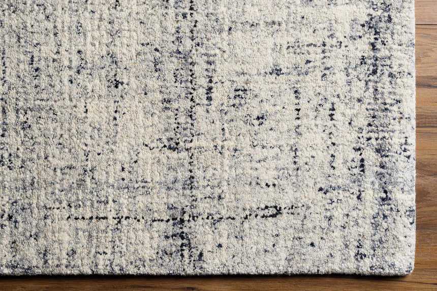 Close-up of the Tanana Area Rug. Cream wool rug with a subtle black and gray contemporary design. Hand-tufted texture. Corner