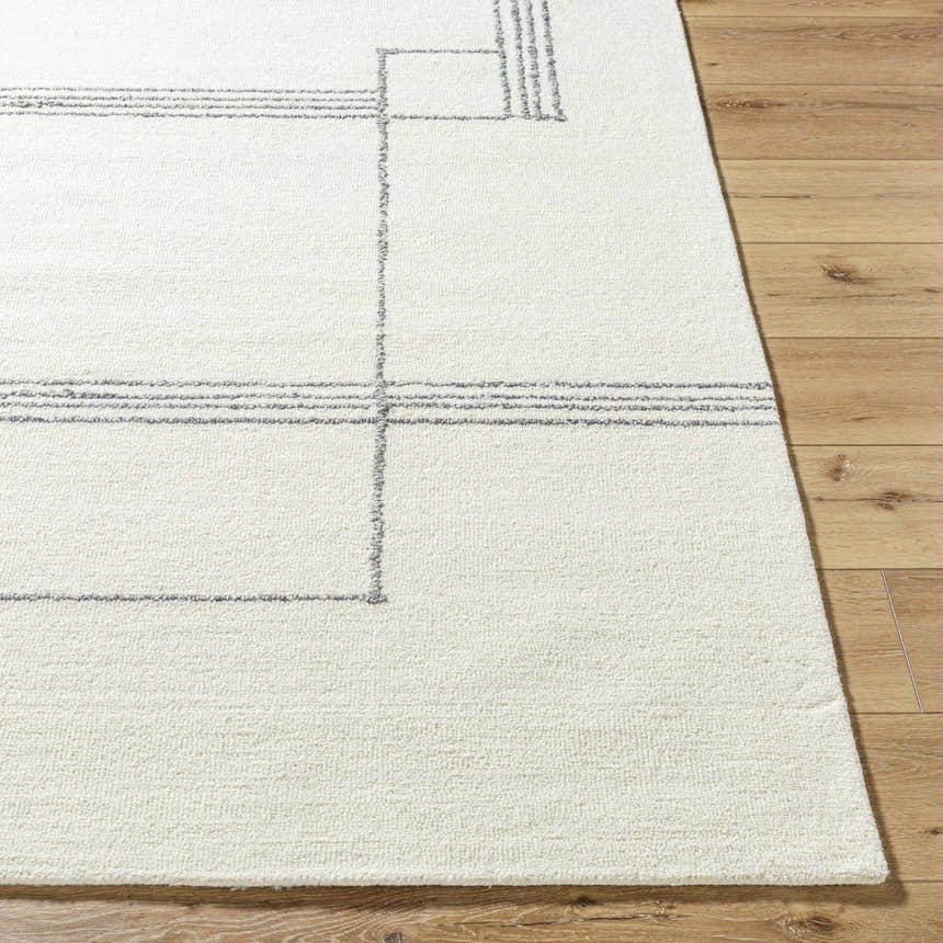Close-up of the hand-tufted Truma Area Rug. Light silver geometric pattern on off-white 100% wool rug. Front