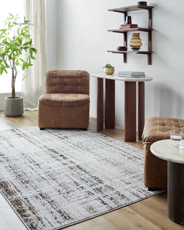 Living room scene with Thora Area Rug in dark brown, denim, and white, paired with brown leather chairs and wooden tables. Roomscene-Rectangle