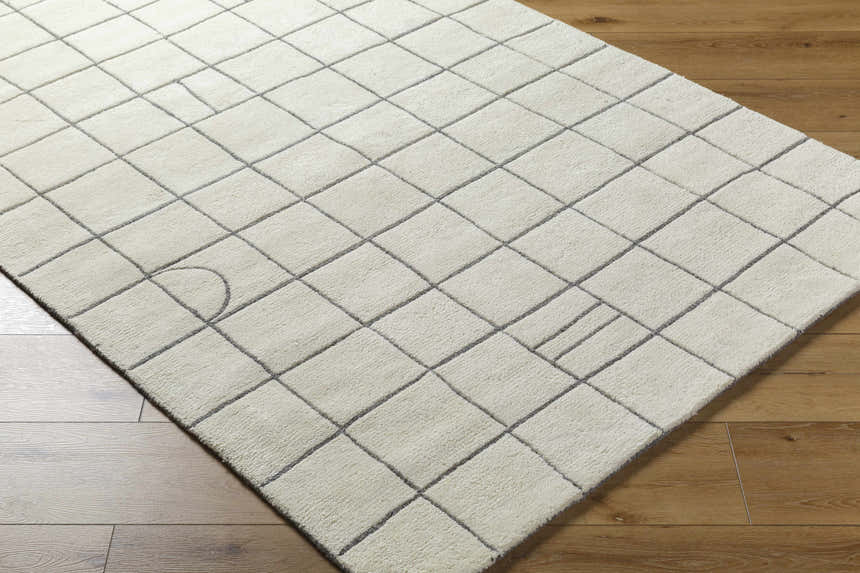 Close-up of Tanya Pearl White Grid Wool Rug on wood floor. Off-white rug with a contemporary square grid pattern. Corner