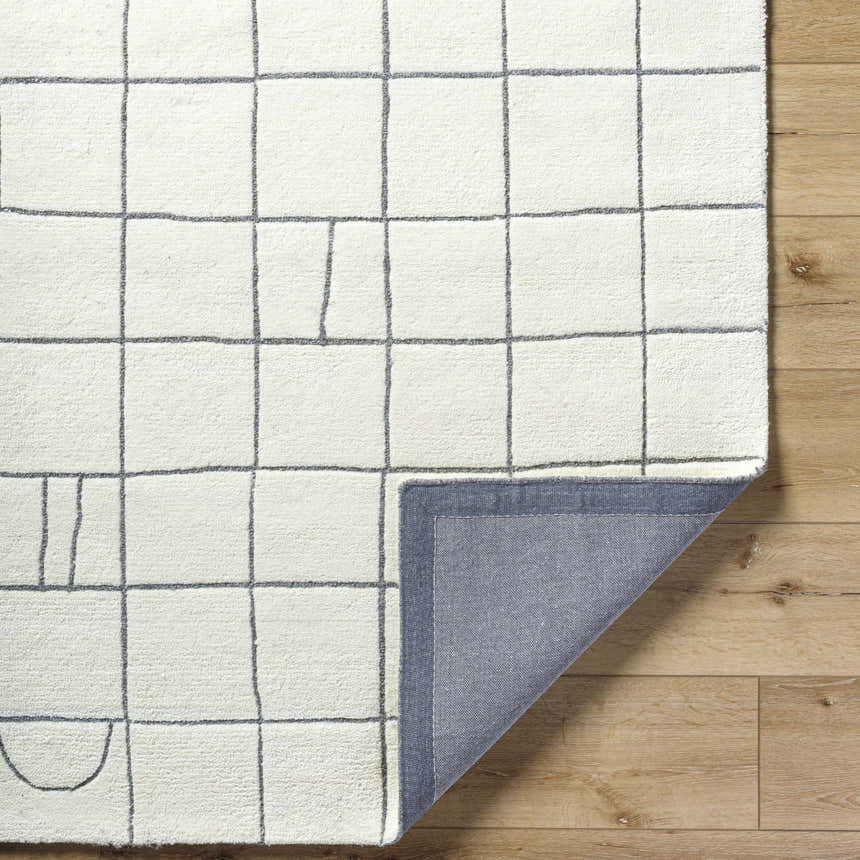 Close-up of the Tanya Pearl White Grid Wool Rug showing its off-white color, grid pattern, and hand-tufted texture. Fold