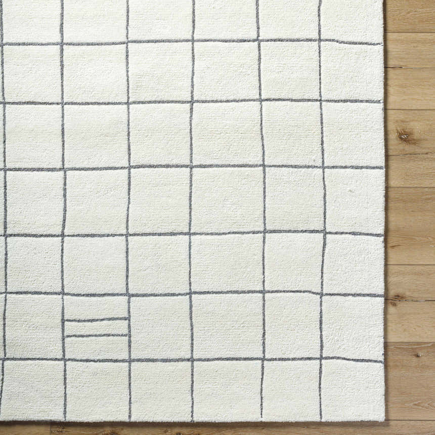 Close-up of the Tanya Pearl White Grid Wool Rug. Hand-tufted, off-white wool with a gray grid pattern. Contemporary style. Corner