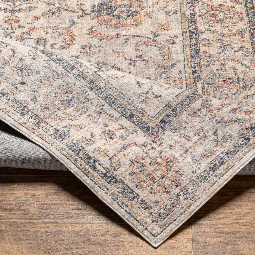 Close-up of the beige Temelec Area Rug with burnt orange, charcoal, and cream floral and oriental design. Machine woven polyester. Fold