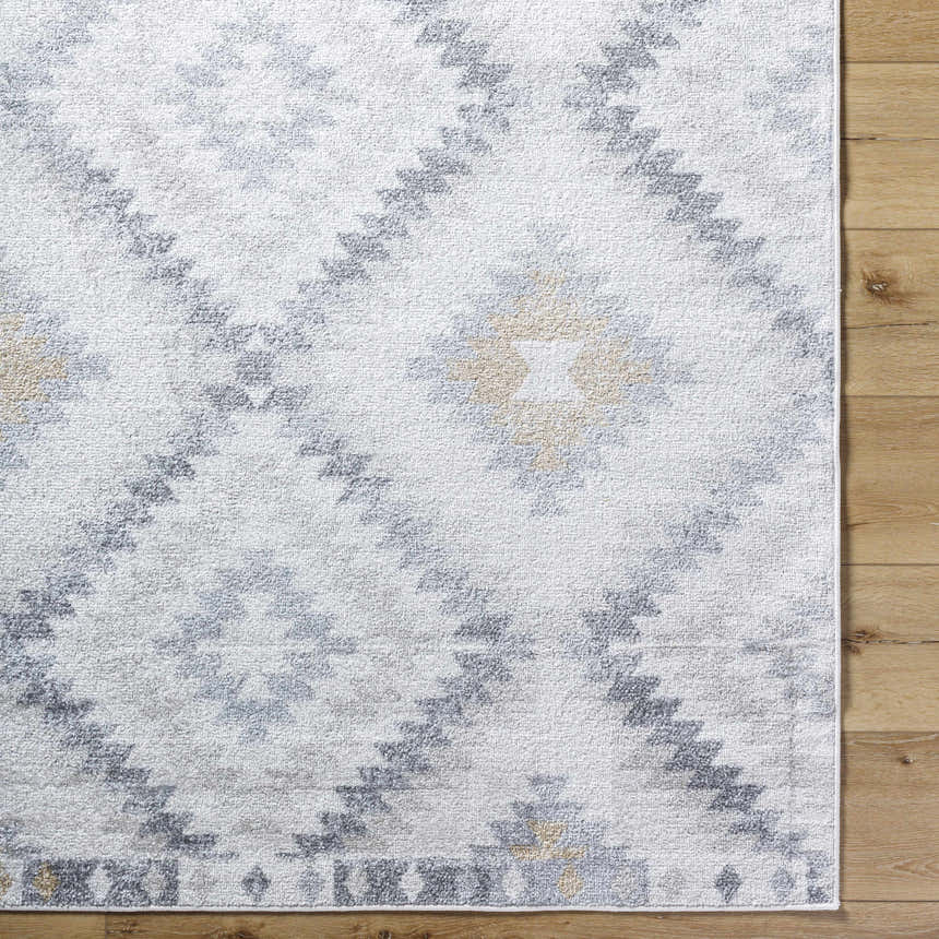Close-up of the Tyipa Area Rug. Southwestern style rug in charcoal, cream, gray, and mustard on a wood floor. Corner
