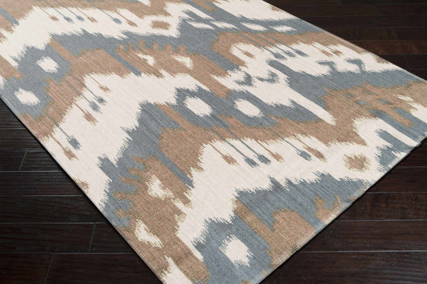Close-up of the Thunderbolt Area Carpet. Light beige wool rug with medium brown, gray, and peach contemporary Southwestern design. Corner