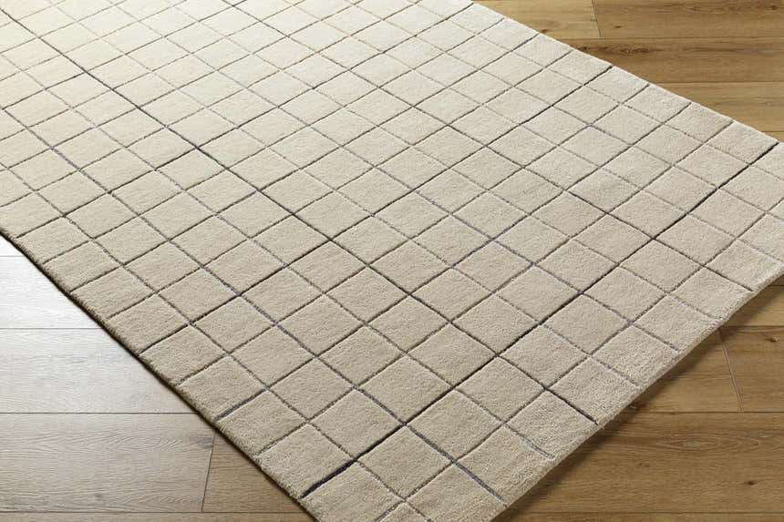 Close-up of the Toshi Beige Area Rug. Hand-tufted wool rug with a contemporary square pattern in tan, gray, and black. Corner