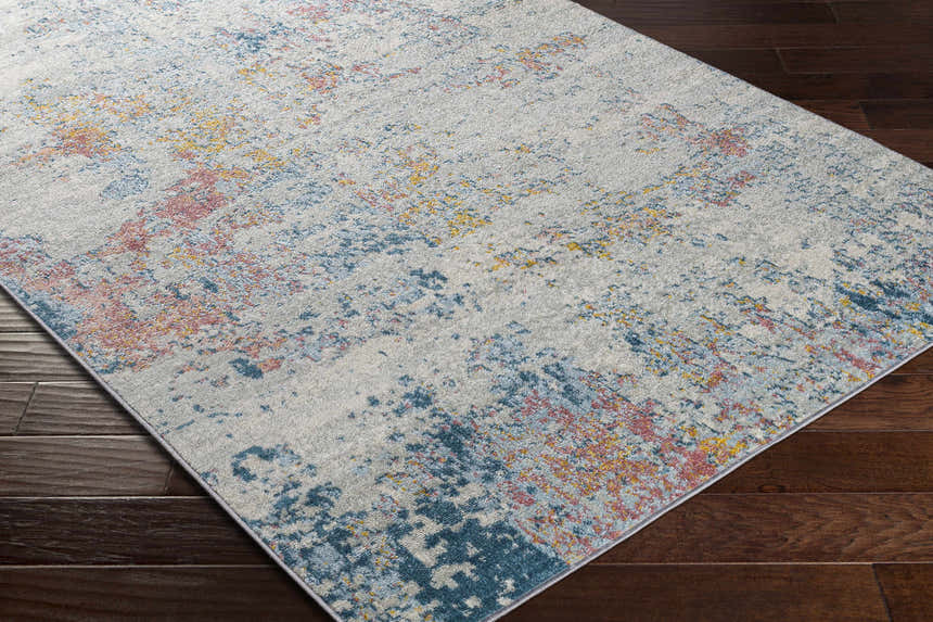 Close-up of Tambalisa Abstract Area Rug featuring cream, coral, blue, and yellow on dark wood floors. Corner