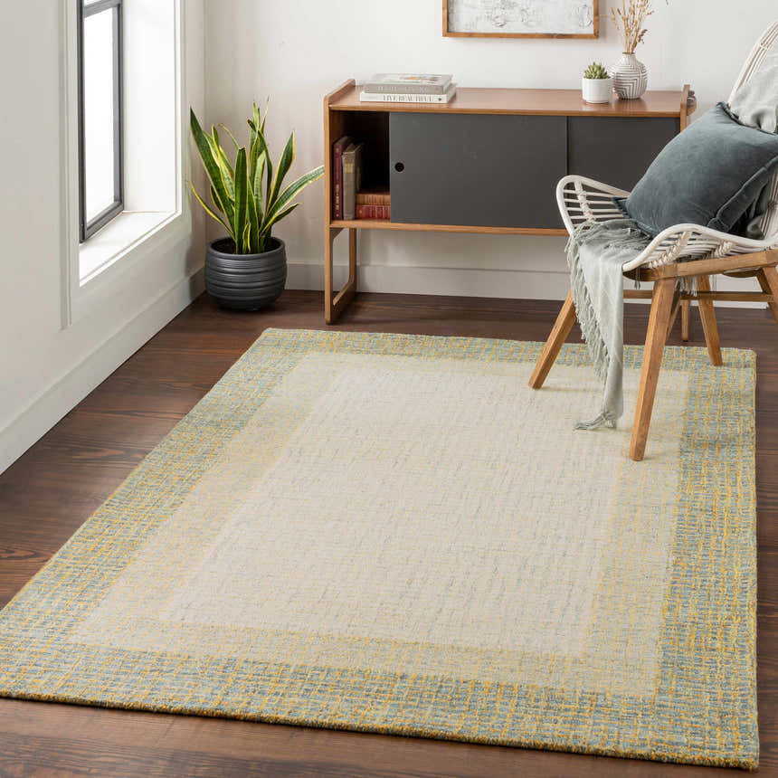 Living room scene with a cream Tandayag Area Rug with sage and light beige accents, styled with a chair and wood cabinet. Roomscene-Rectangle