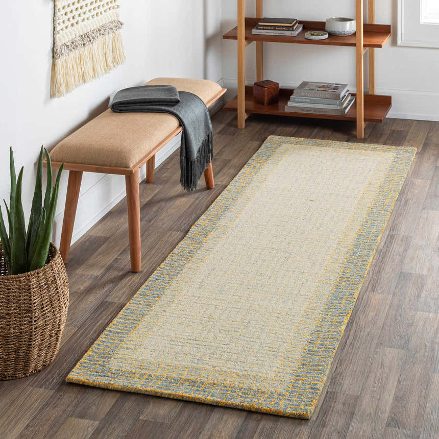 Hallway scene with a cream and sage Tandayag Area Rug, wood bench, woven wall art, and a plant in a basket. Roomscene-Runner