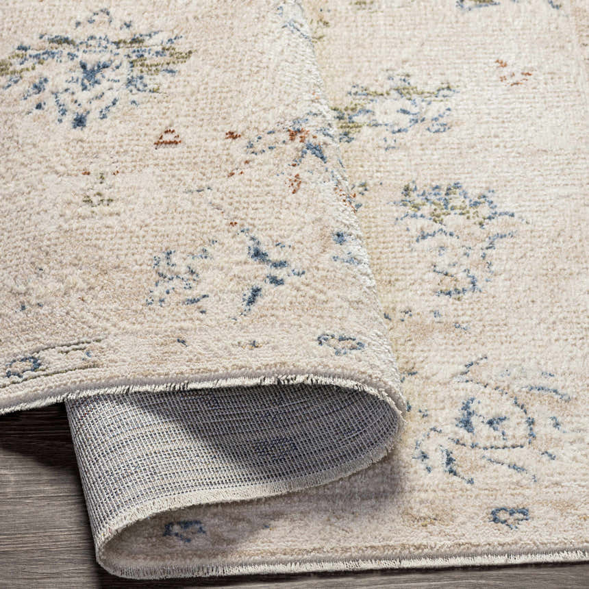 Close up of the Tinampo Area Rug showing the cream, blue, and olive floral pattern and texture. Fold