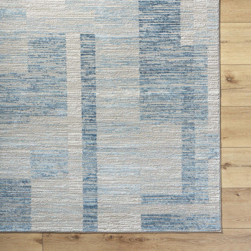Close-up of the Teman Area Rug showing a contemporary blue and ivory geometric pattern and textured weave. Corner