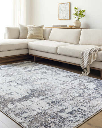 Living room scene with a light beige sectional sofa and the Tycho Area Rug in light silver, silver gray, and slate blue. Roomscene-Rectangle