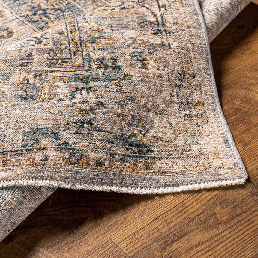 Close-up of the Tuganay Luxe Performance Rug showing its beige, blue, and mustard colors and traditional pattern. Fold