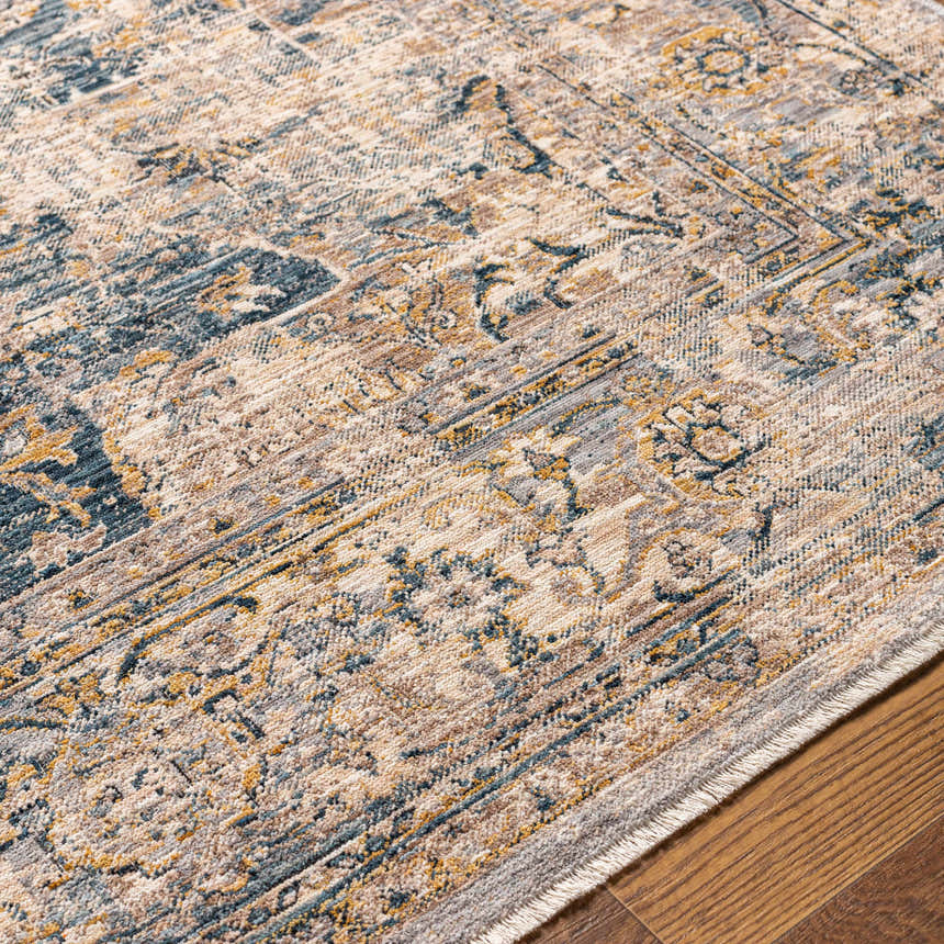 Close-up of the Tuganay Luxe Performance Rug. Beige, blue, and mustard tones in a traditional, distressed pattern. Machine woven rug. Texture