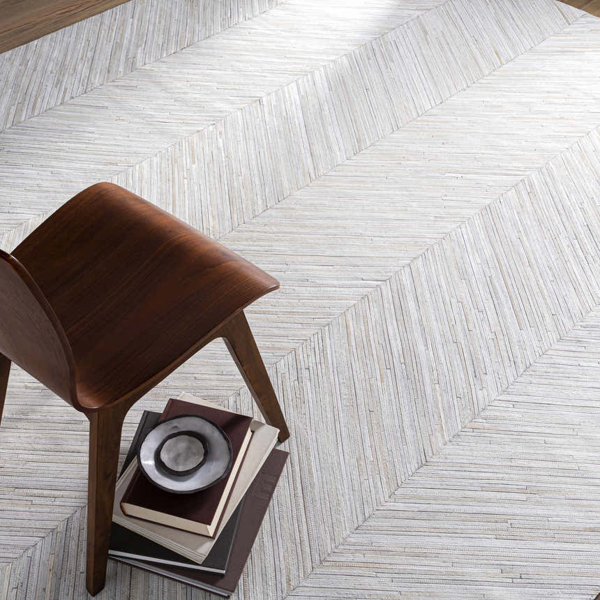 Close-up of the cream and brown Upland Premium Rug with a chevron pattern and a wood chair. Styleshot