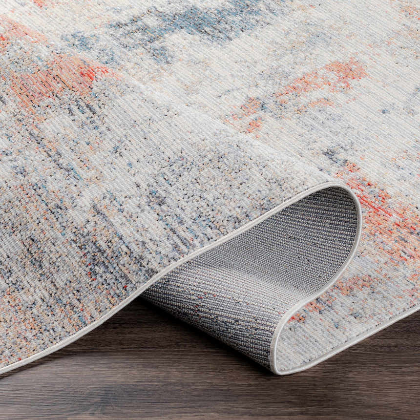 Close-up of the Upminster Area Rug showing its brick red, teal, and light beige coastal pattern and machine woven texture. Fold