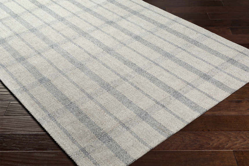 Close-up of the hand woven Verdon Light Gray Plaid Rug showing gray and oatmeal stripes on dark wood flooring. Corner