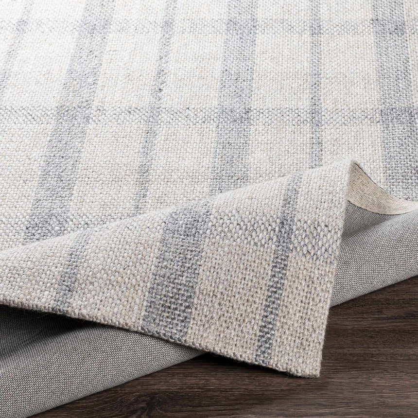Close-up of the Verdon Light Gray Plaid Rug showing texture and pattern. Hand-woven wool and viscose rug in gray, oatmeal, and light gray. Fold