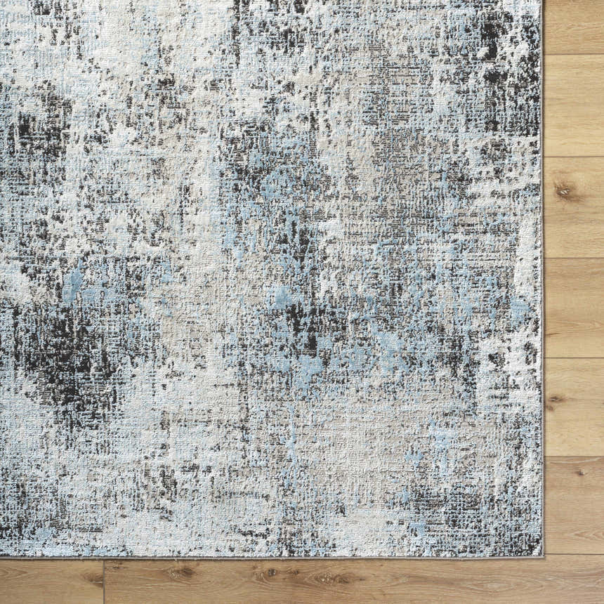 Close-up of the Vesna Blue Area Rug showing its Southwestern design, and blue, charcoal, and ivory colors. Corner