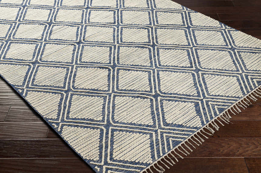Close-up of the hand woven Walgett Carpet Area Rug. Blue geometric pattern on cream cotton with fringe detail. Corner