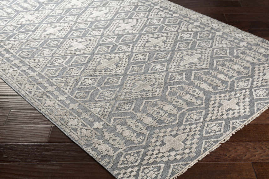 Close-up of the hand-knotted Woodsfield Premium Rug. Beige and gray geometric pattern on a wool rug with a traditional style. Corner