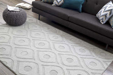 Living room scene with a light gray Welaka Eye Pattern Wool Rug, charcoal sofa, and gray pouf. Roomscene-Rectangle