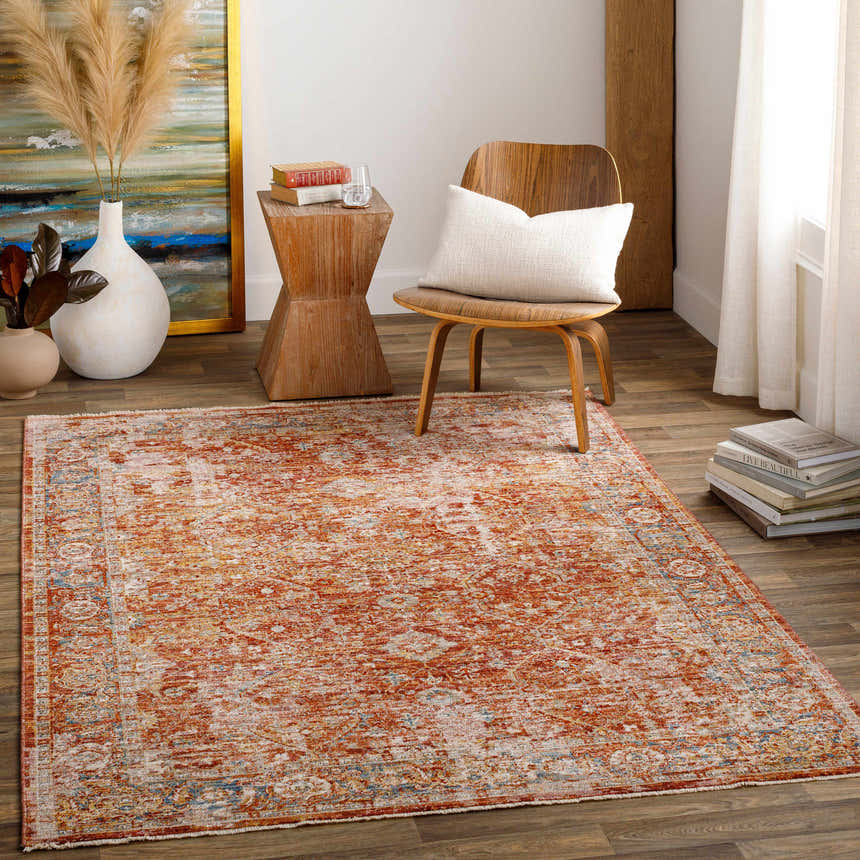 Living room scene with a rust-colored Wetaskiwin Area Rug, wood floors, chair with pillow, and decorative accents. Roomscene-Rectangle
