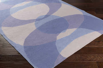 Close-up of the hand woven Whitnash Area Rug, featuring a contemporary blue, lavender, and cream geometric pattern. Corner