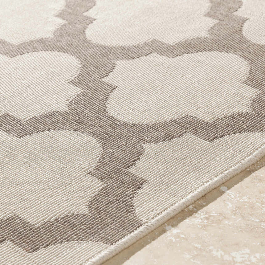 Close-up of the Winterville Area Rug showing beige and dark red quatrefoil pattern and olefin texture. Texture