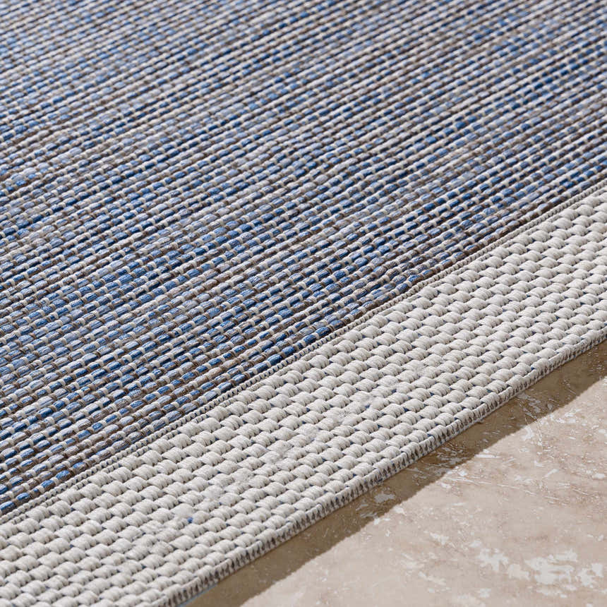 Close-up of the woven texture of the Wishon Area Rug. Colors include blue, cream, and taupe. Texture