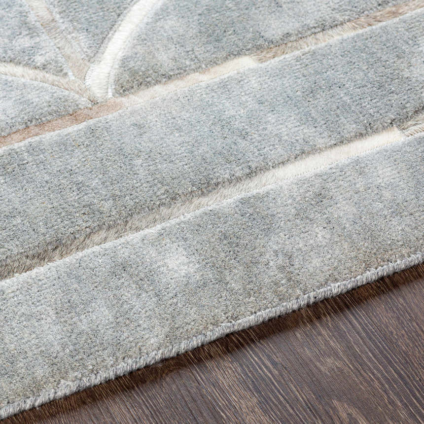 Close-up of the hand-crafted Willingham Area Rug; charcoal, light beige, and gray viscose texture on wood floor. Texture