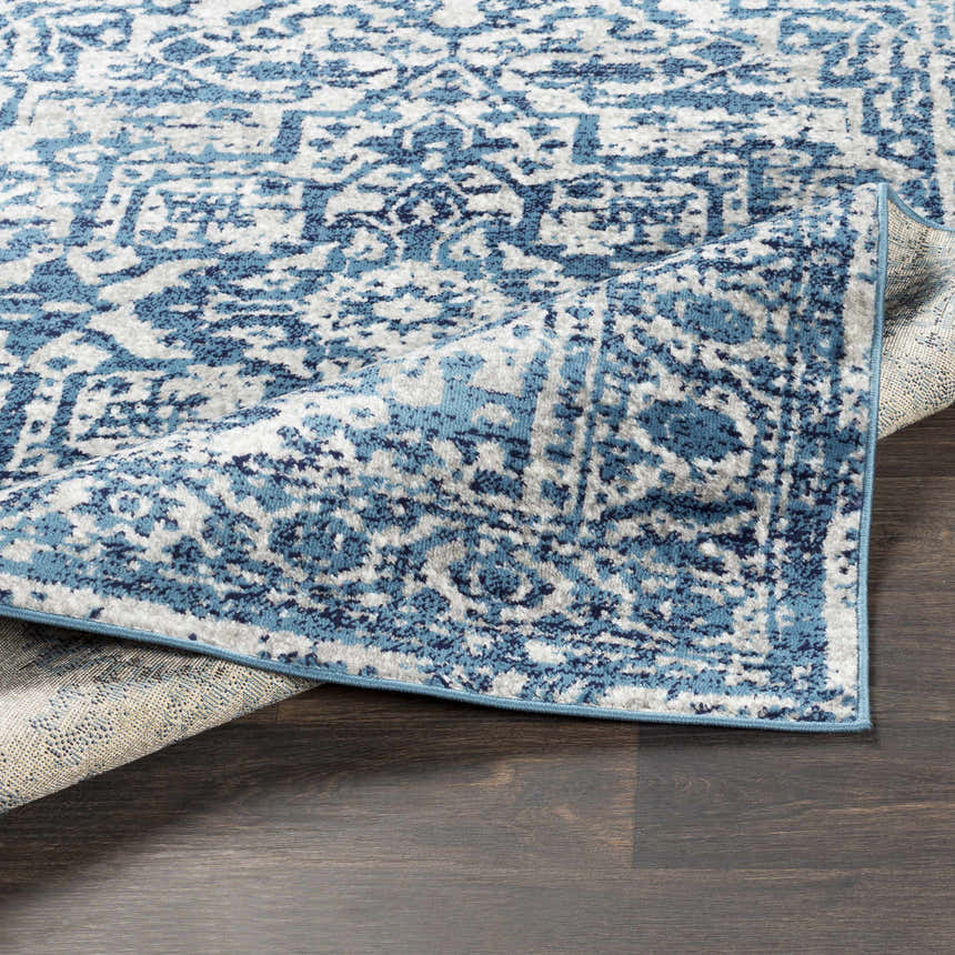 Close-up of the Wellsblue Traditional Rug showing its blue, light gray, and white vintage-inspired pattern and soft texture. Fold