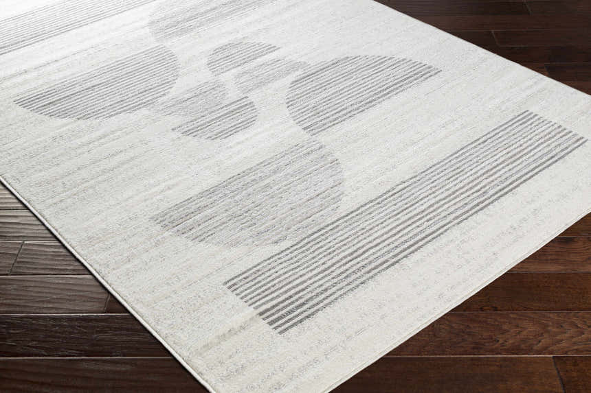 Close-up of the Westcourt Area Rug showing its geometric pattern in dark gray, nickel, pewter, and silverton on dark wood floor. Corner