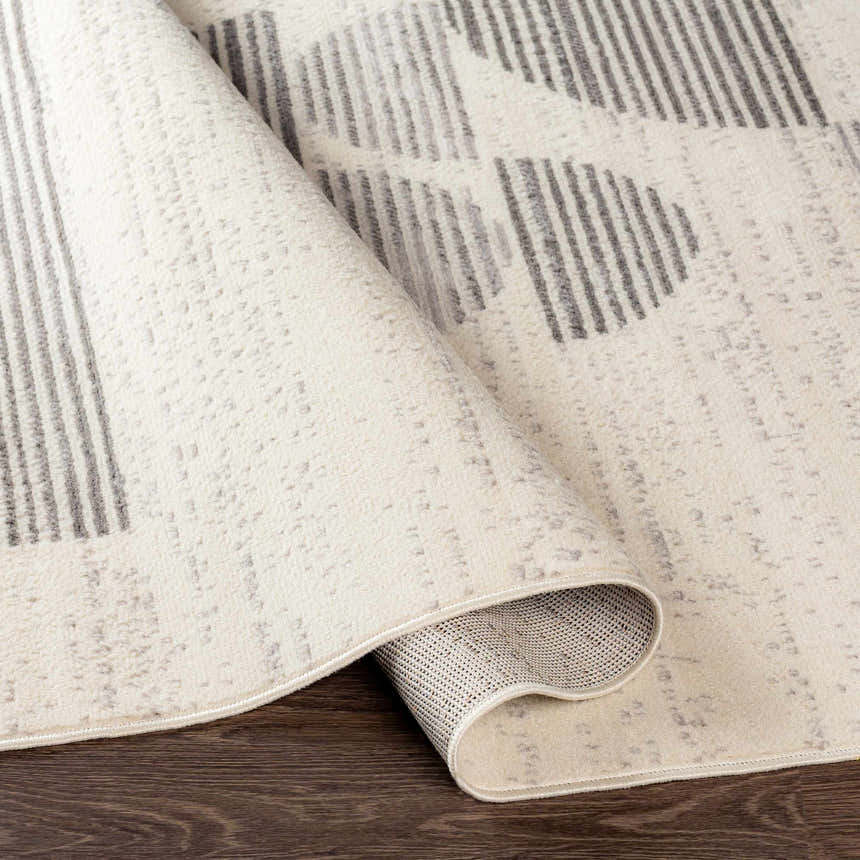 Close up of the Westcourt Area Rug showing its dark gray geometric pattern and polypropylene texture. Fold