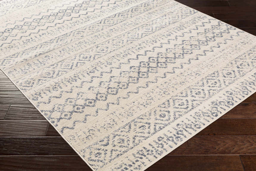 Close-up of the Westborough Beige Area Rug showing a contemporary blue geometric pattern on a cream background. Corner