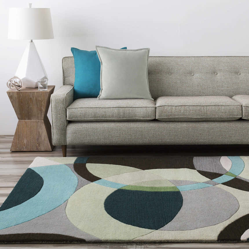 Living room scene with a gray sofa and the Wyocena Wool Rug in aqua, gray, and green geometric shapes. Roomscene-Rectangle