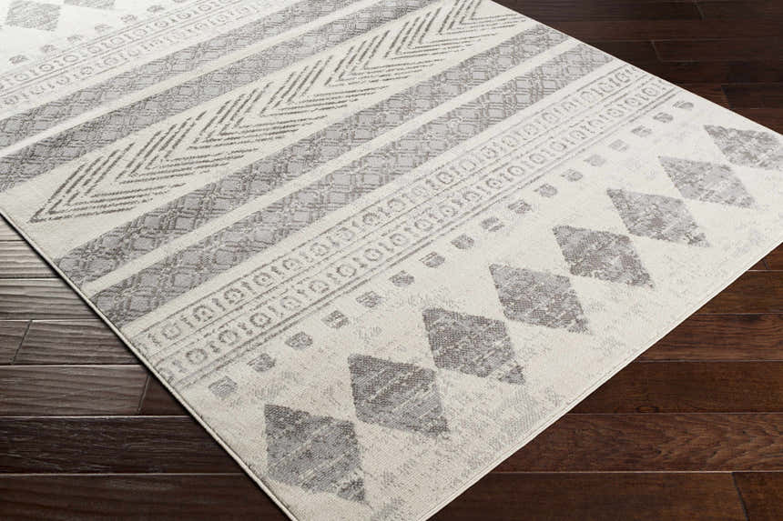 Close-up of the Wyoming Area Rug. Bohemian style rug in charcoal, gray, and off-white with geometric patterns. Corner