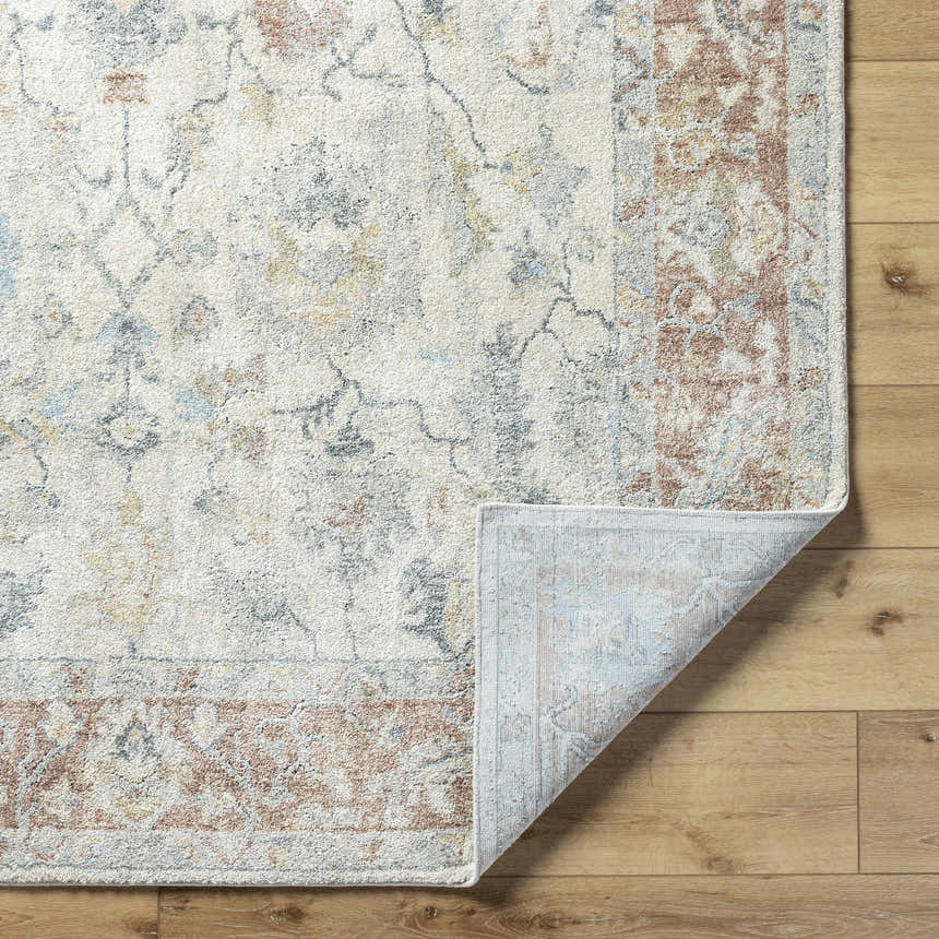 Close-up of the Yetta Beige Thick Luxe Area Rug showing its traditional floral pattern and colors on a wood floor. Fold