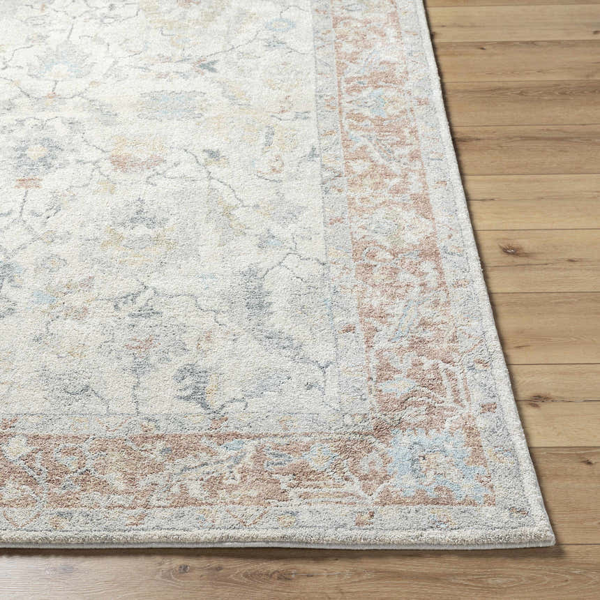 Close-up of the Yetta Beige Thick Luxe Area Rug showing its traditional design, beige tones, and pink border on wood floor. Front