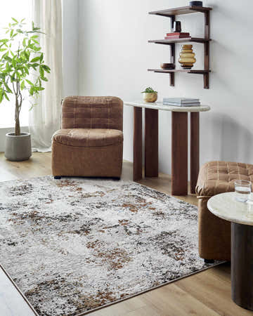 Living room scene with brown leather chair and Zaria Area Rug in dark brown, denim, and white. Roomscene-Rectangle