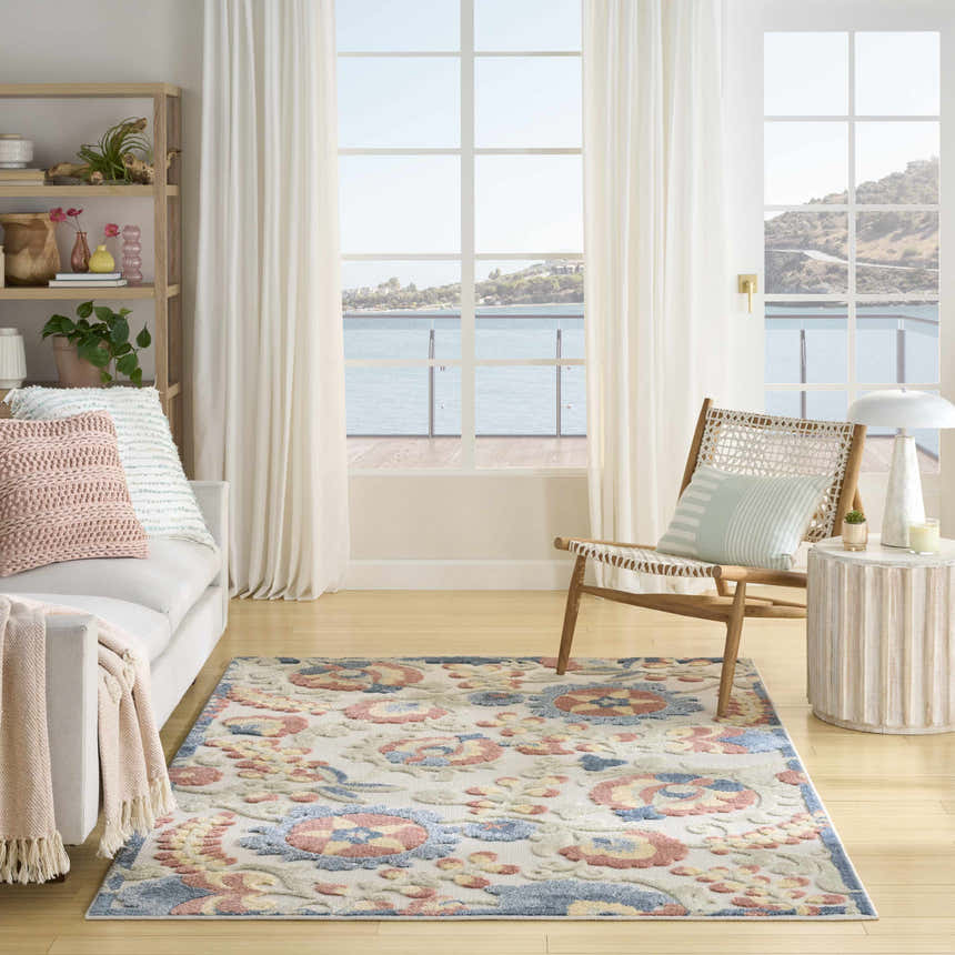 Coastal living room with a Nourison Aloha Grey Multicolor Farmhouse Area Rug, white sofa, and ocean view.
