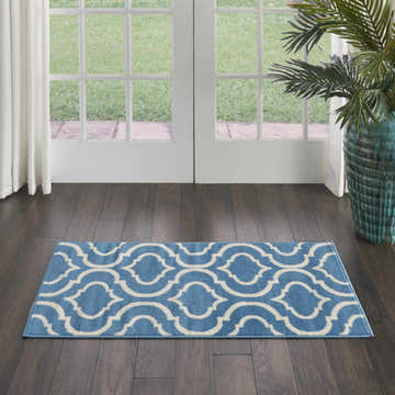Entryway with Nourison Jubilant Blue rug, dark wood floors, white doors, and a potted plant.