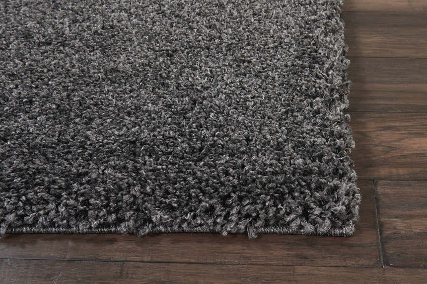 Close-up of the dark gray Nourison Malibu Shag rug showing its plush texture on dark wood flooring.