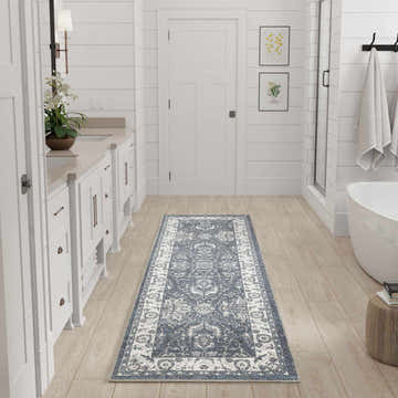 Bathroom scene with Nourison Astra Slate Vintage Rug runner, white cabinets, and light wood floors.