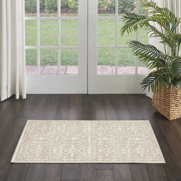 Entryway scene with Nourison Jubilant Ivory Beige rug on dark wood floors, white doors, and a potted palm. Farmhouse style.
