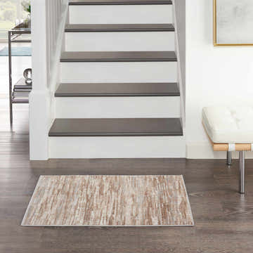 Entryway with Nourison Elation Ivory Grey rug on dark wood floor, white stairs, and modern bench.