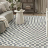 Living room scene with a Nourison Serenity Home Ivory Blue rug featuring a checkerboard pattern, sofa, and side table.