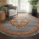 Living room scene with round Nourison Passionate Grey Bohemian rug, armchair, woven side table, and potted plant.